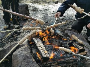 Barn steker pinnebrød på bål