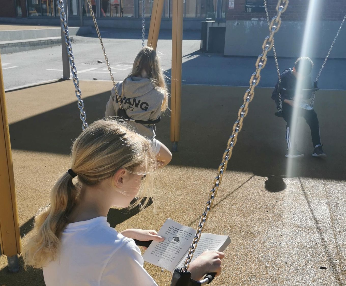 Elever sitter i husker mens de leser i sola