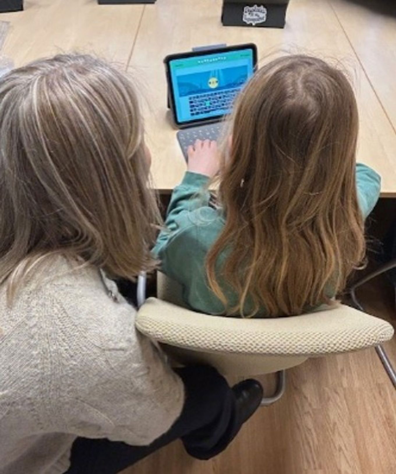 To barn sitter ved et bord og ser på et nettbrett